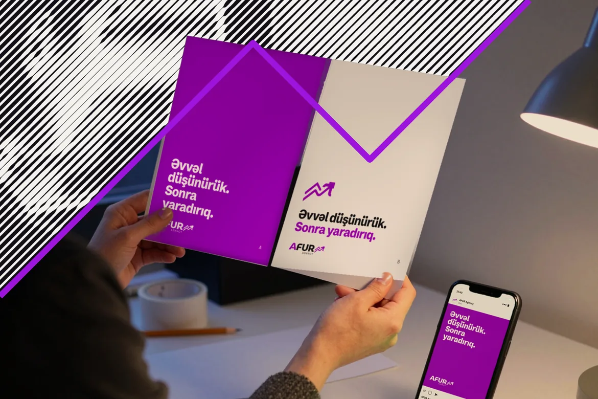 Marketoloq AFUR reklamının A və B çap variantlarından birini seçir; yanındakı telefonda lent açıqdır.